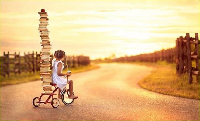Mergina ant dviračio su kalnu knygų saulėlydžio metu
